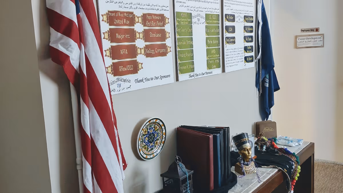 American flag beside wall-mounted posters, a desk with binders, and decorative items.