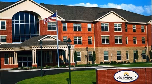 Paramount Senior Living Bethel Park exterior features a brick building, grand front entrance, and flag.
