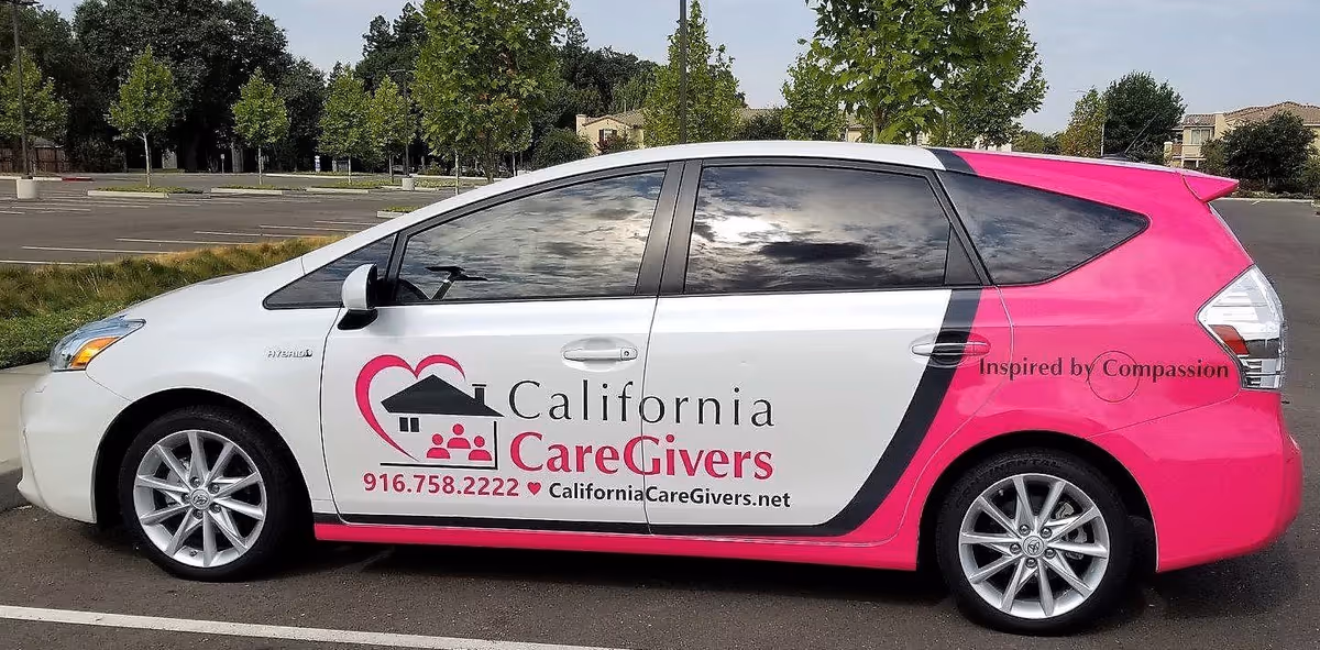 A white and pink California CareGivers promotional van parked in a parking lot.