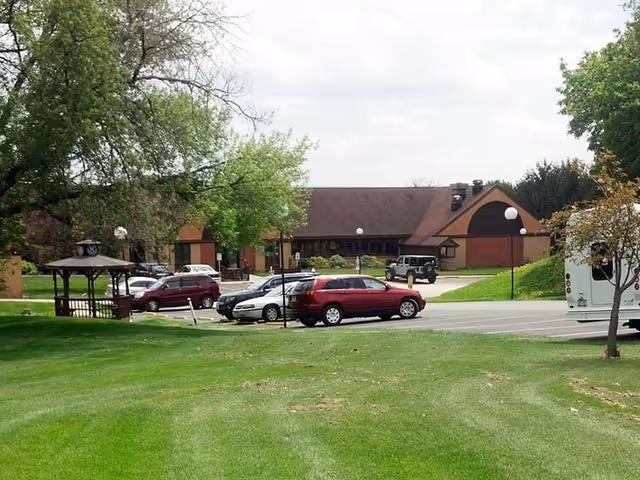 Exterior view of Clinton Crest Manor with a parking lot and green lawn.