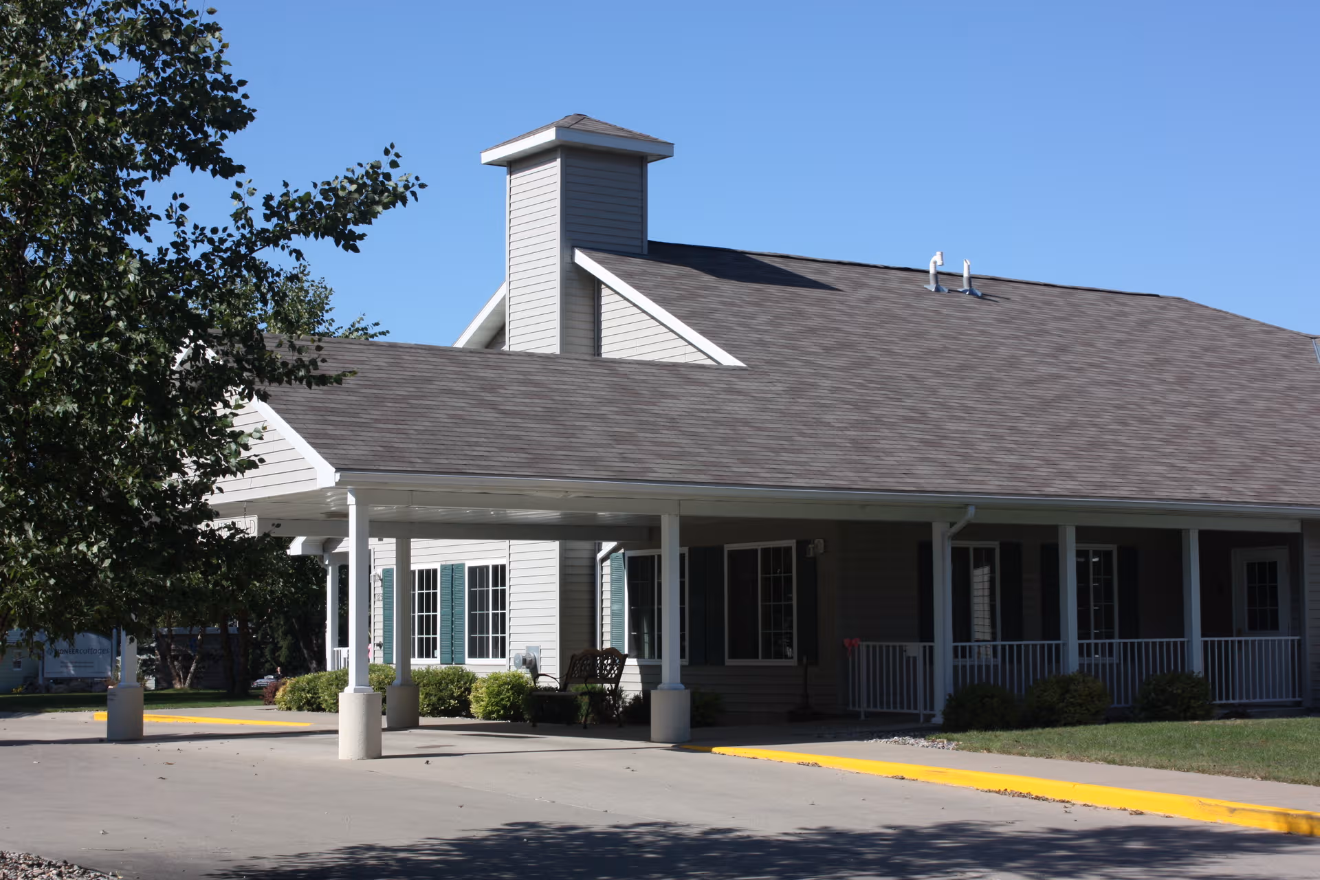 Front exterior of a memory care facility with a covered entrance and landscaping.