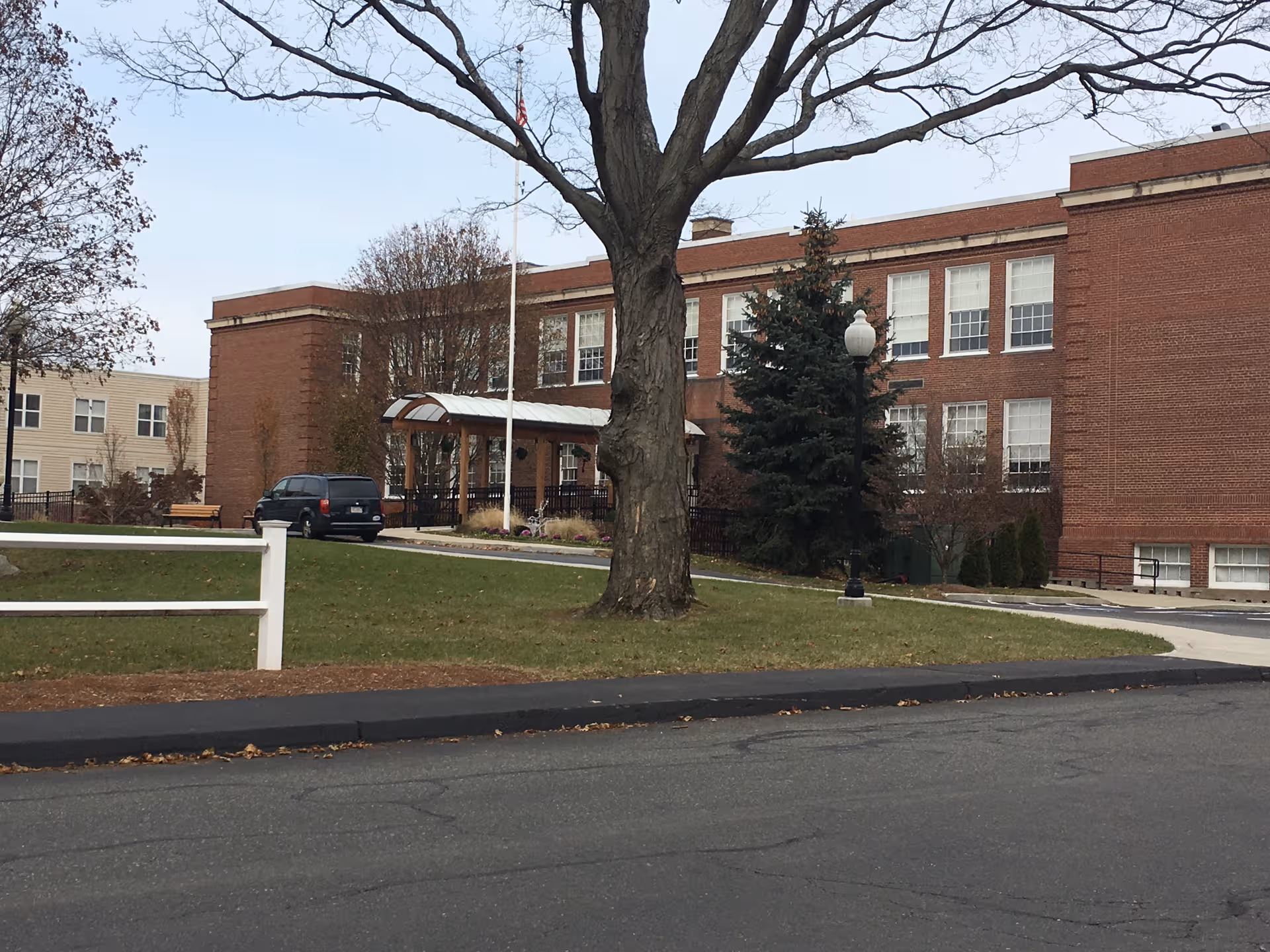 Exterior view of brick senior living building with entrance canopy and surrounding lawn.