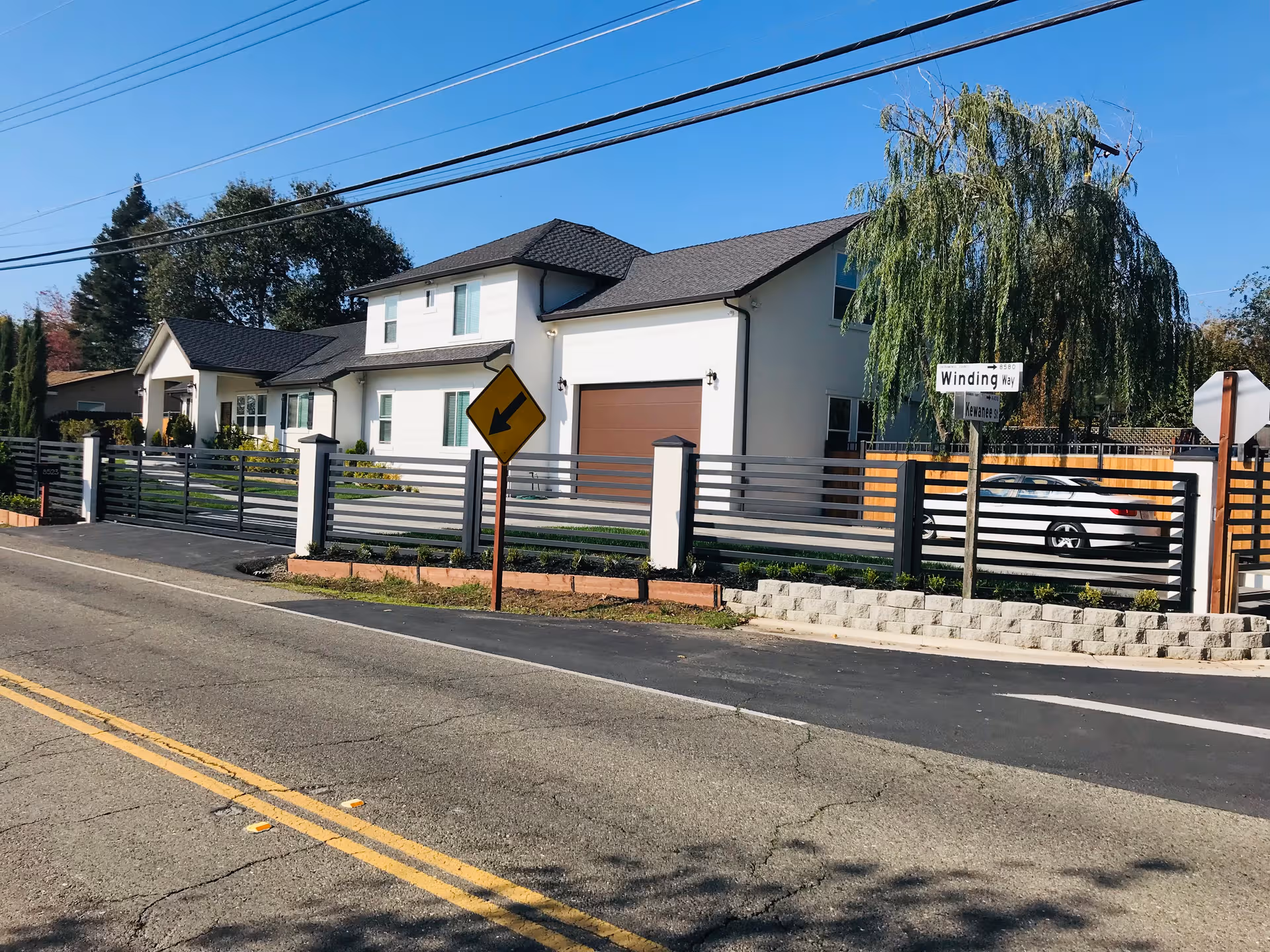 Two-story Pearl Care Assisted Living building with modern gray fence along a street.