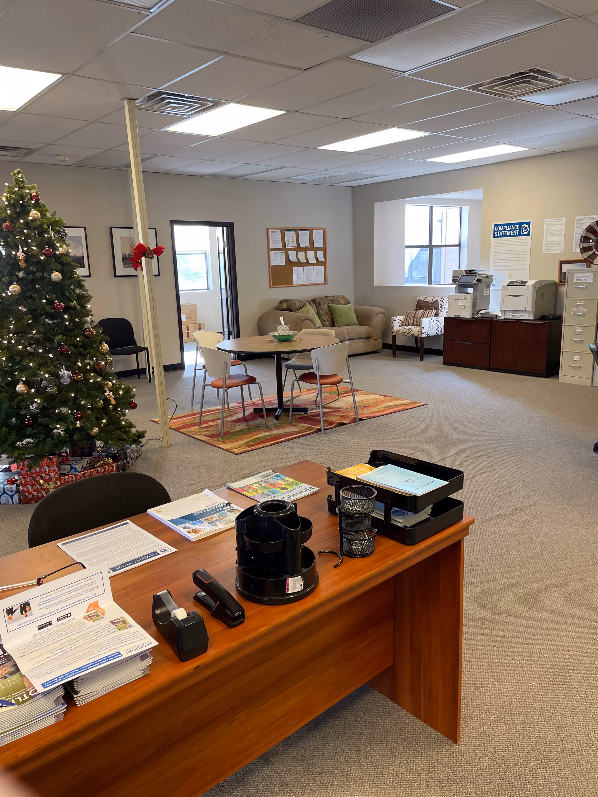 Spacious reception area with Christmas tree, round table, sofa, and office equipment.