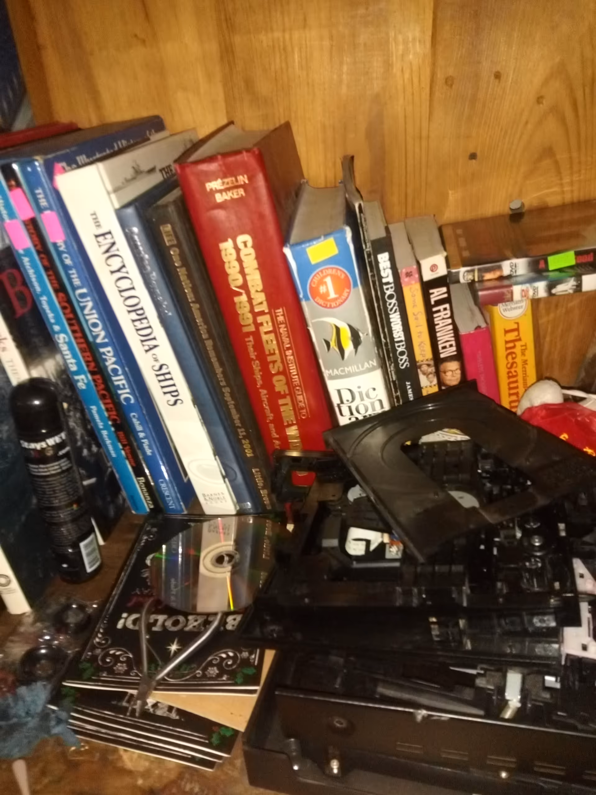 Cluttered wooden shelf filled with books, CDs, and electronic equipment.