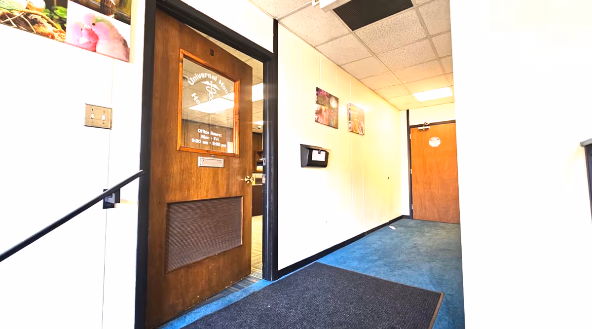 Interior hallway of Universal Home Health Care facility with wooden door and blue carpet.