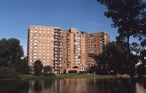 Exterior view of Pecan Creek Healthcare Center, a large brick building by a pond.
