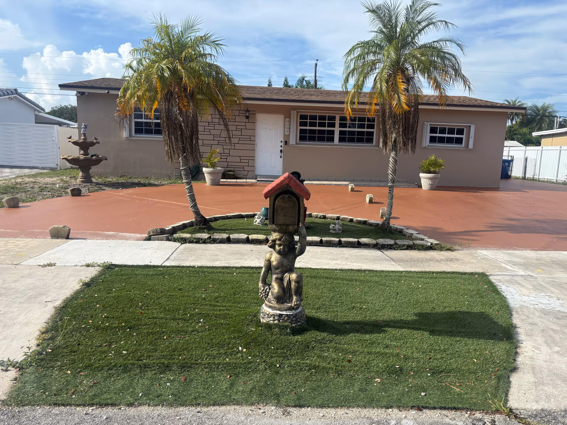 Exterior view of Mi Hogar INC, a single-story facility with a red driveway, palms, and statue.