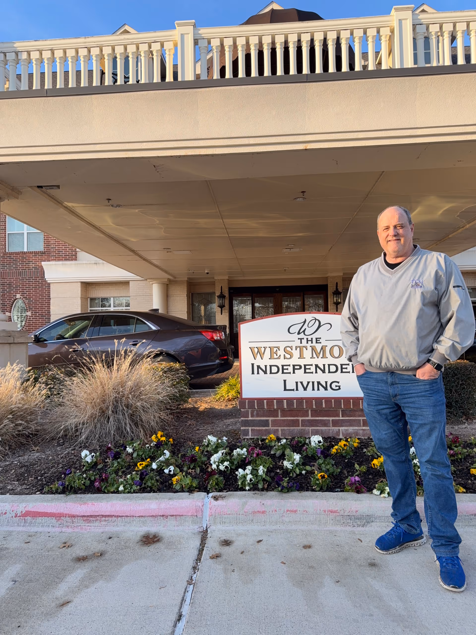 Man stands outside The Westmore Independent Living entrance beside a landscaped sign.