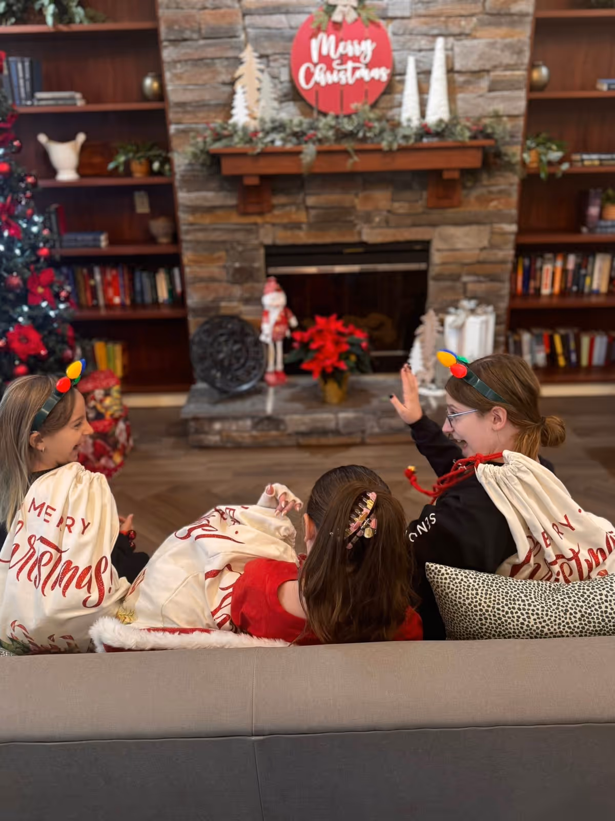 Group of people sit on a sofa in a cozy living room with Christmas decor.