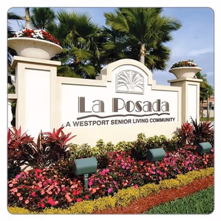 La Posada entrance sign with tropical landscaping and colorful flowers.