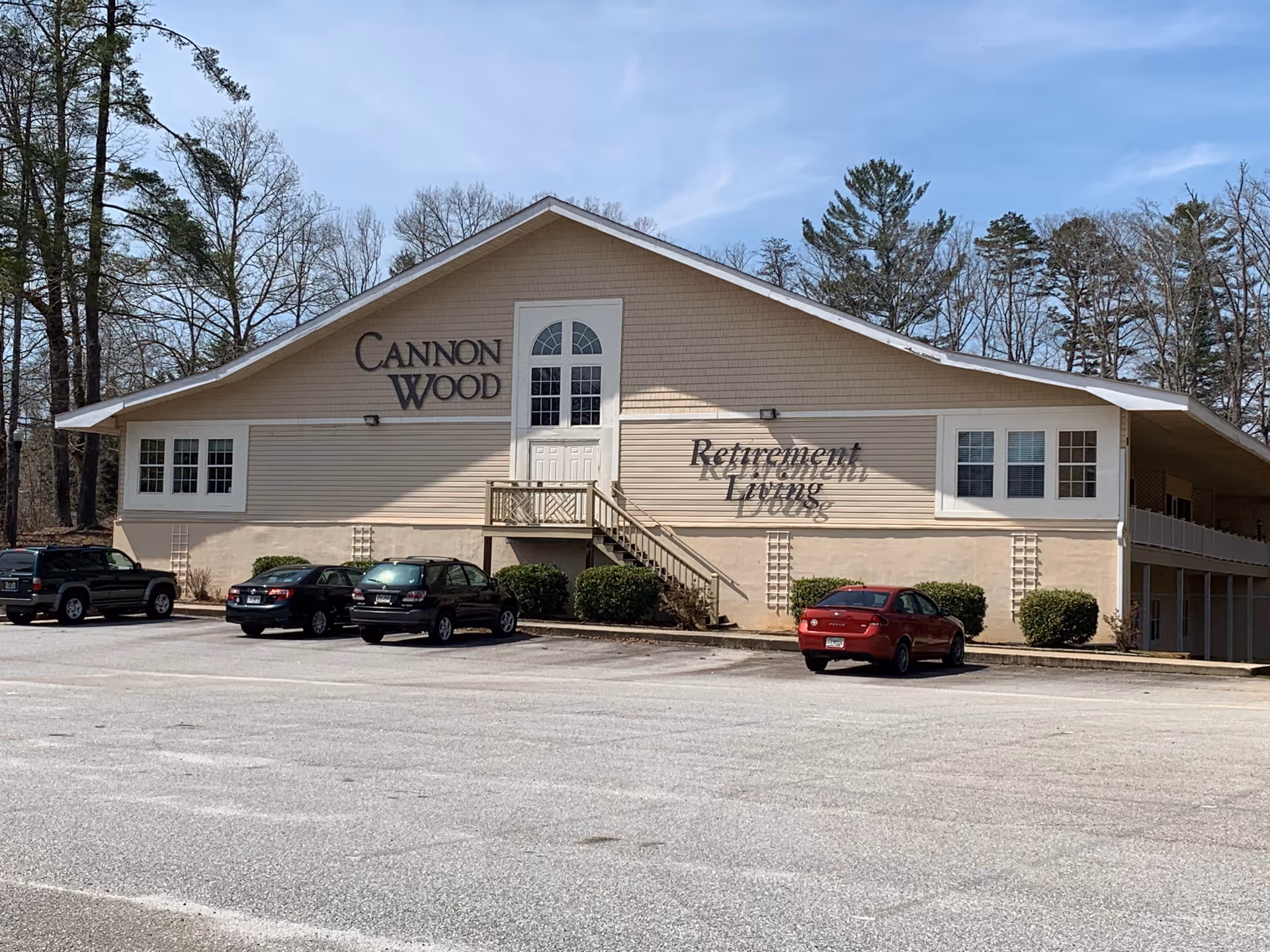 Front exterior of Cannonwood Village Retirement Living with parked cars and trees.