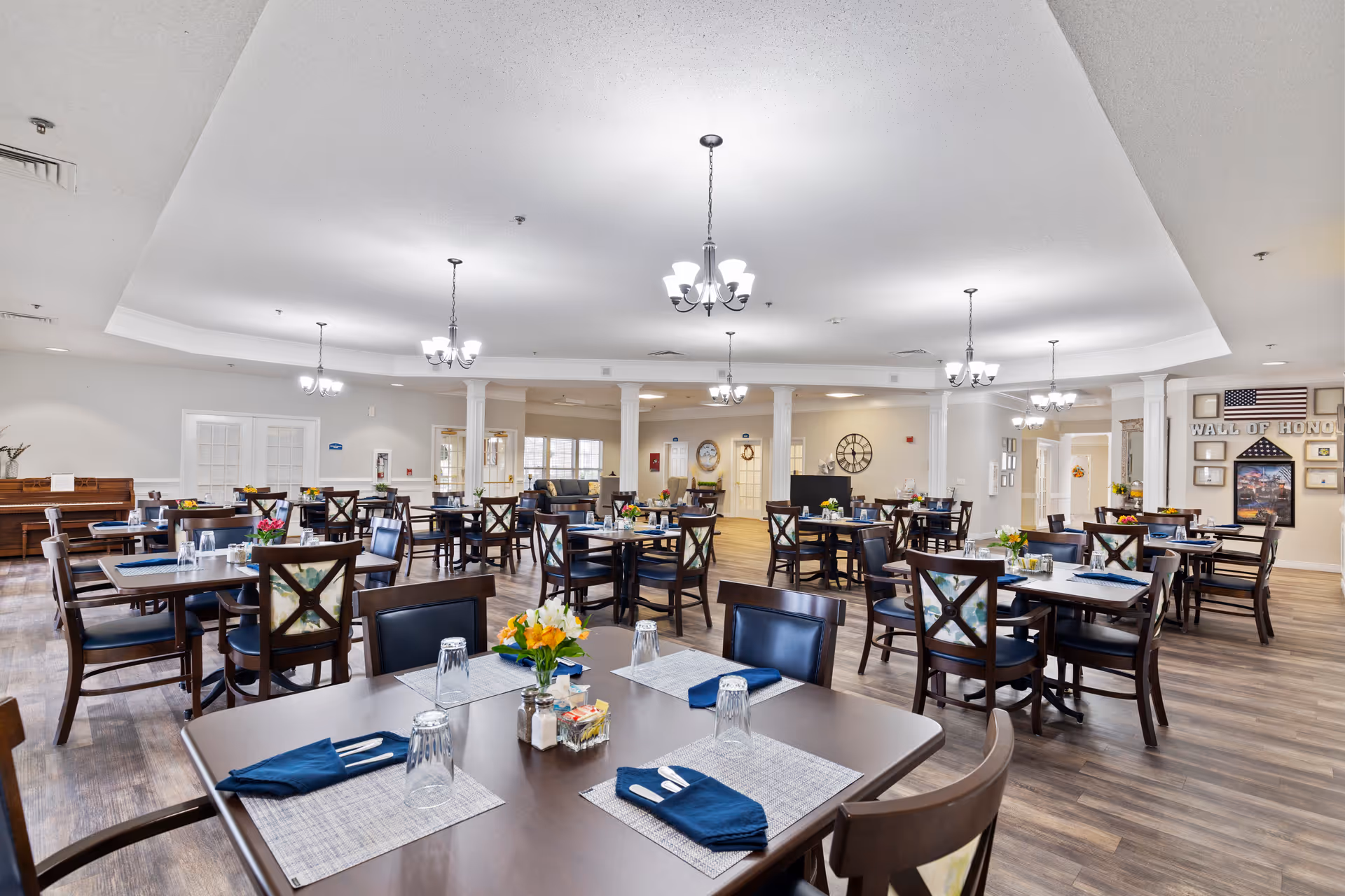 A spacious senior dining room with multiple tables, chairs, and colorful centerpieces.