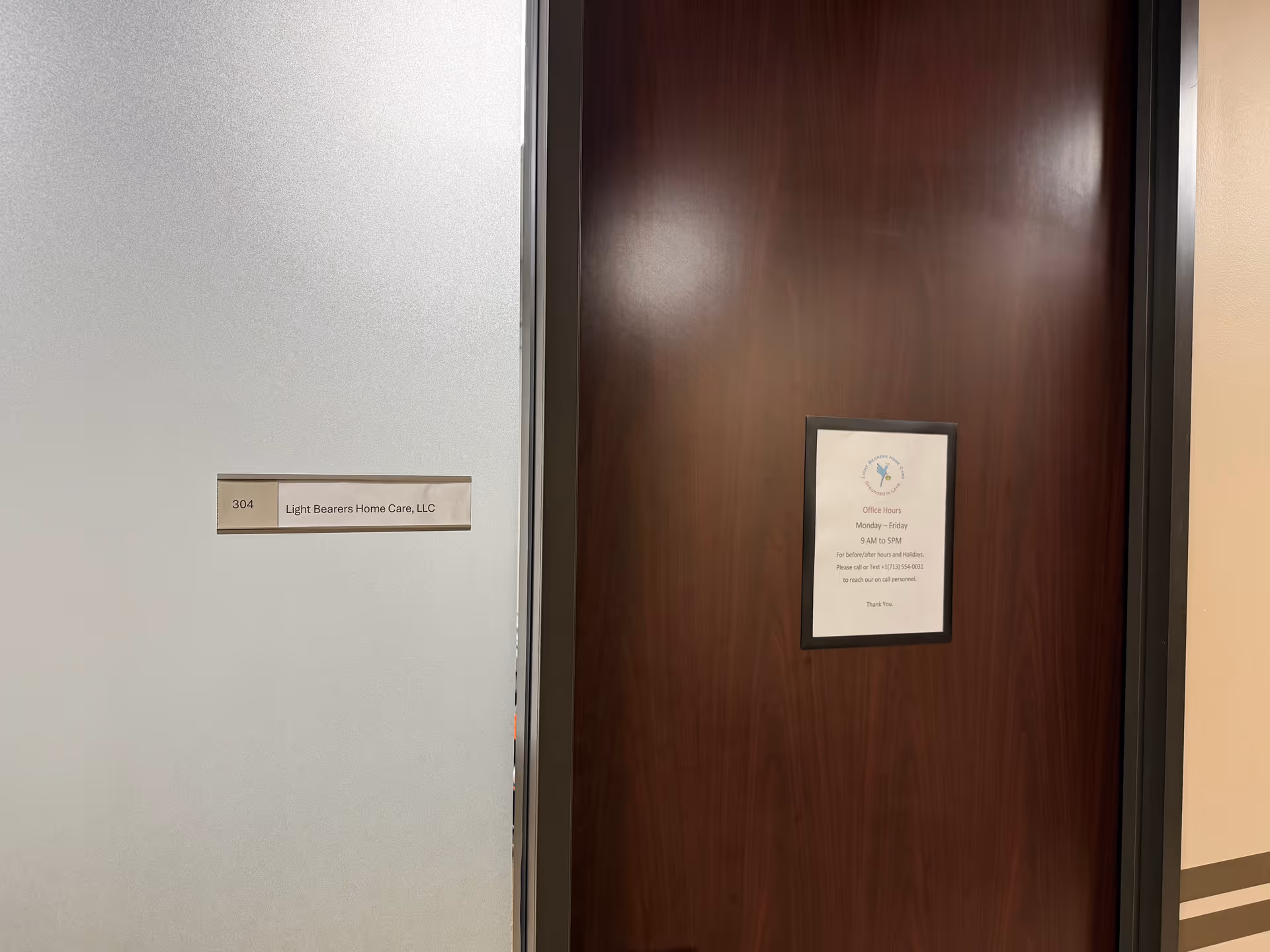 Interior hallway with a wooden door and a plaque for Light Bearers Home Care, LLC.