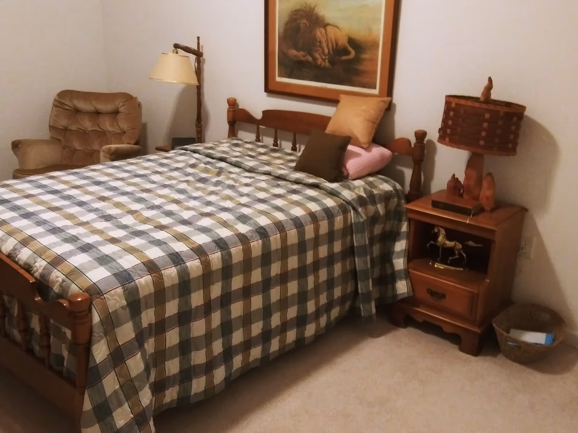 Cozy bedroom with a wooden bed, plaid quilt, nightstand, and chair.