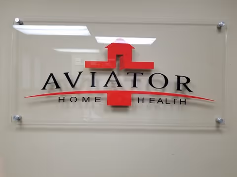 Clear acrylic wall sign displaying Aviator Home Health logo and red medical cross