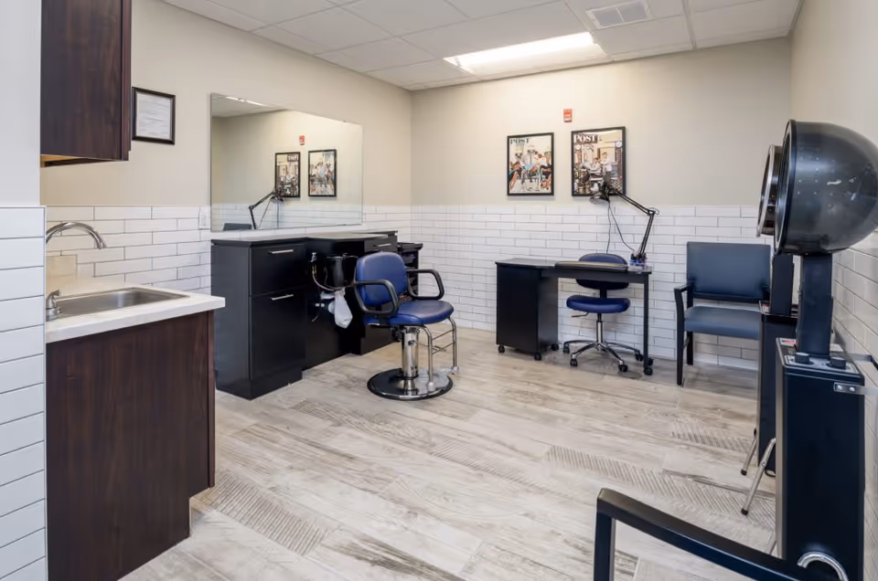 A senior living facility hair salon with styling chairs, mirrors, sinks, and a hood dryer.