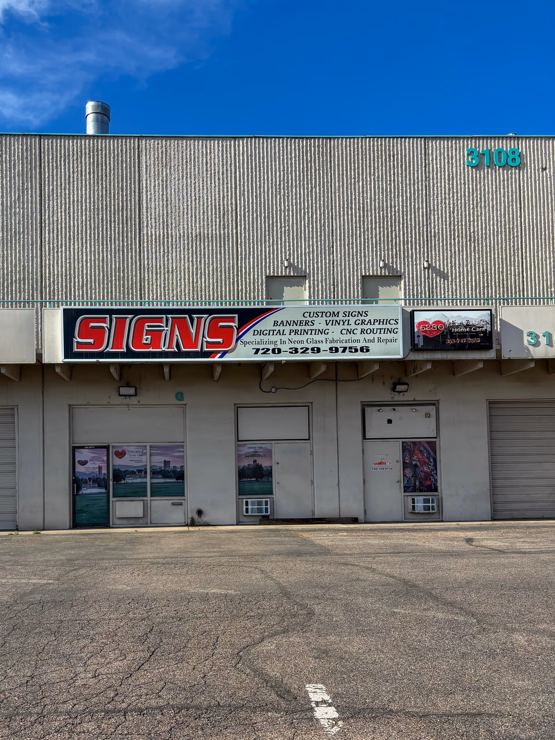 Exterior storefront with a large SIGNS sign, several doors, and window posters.