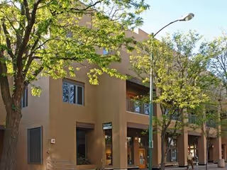 Exterior view of a beige, multi-story senior facility with trees along the sidewalk.