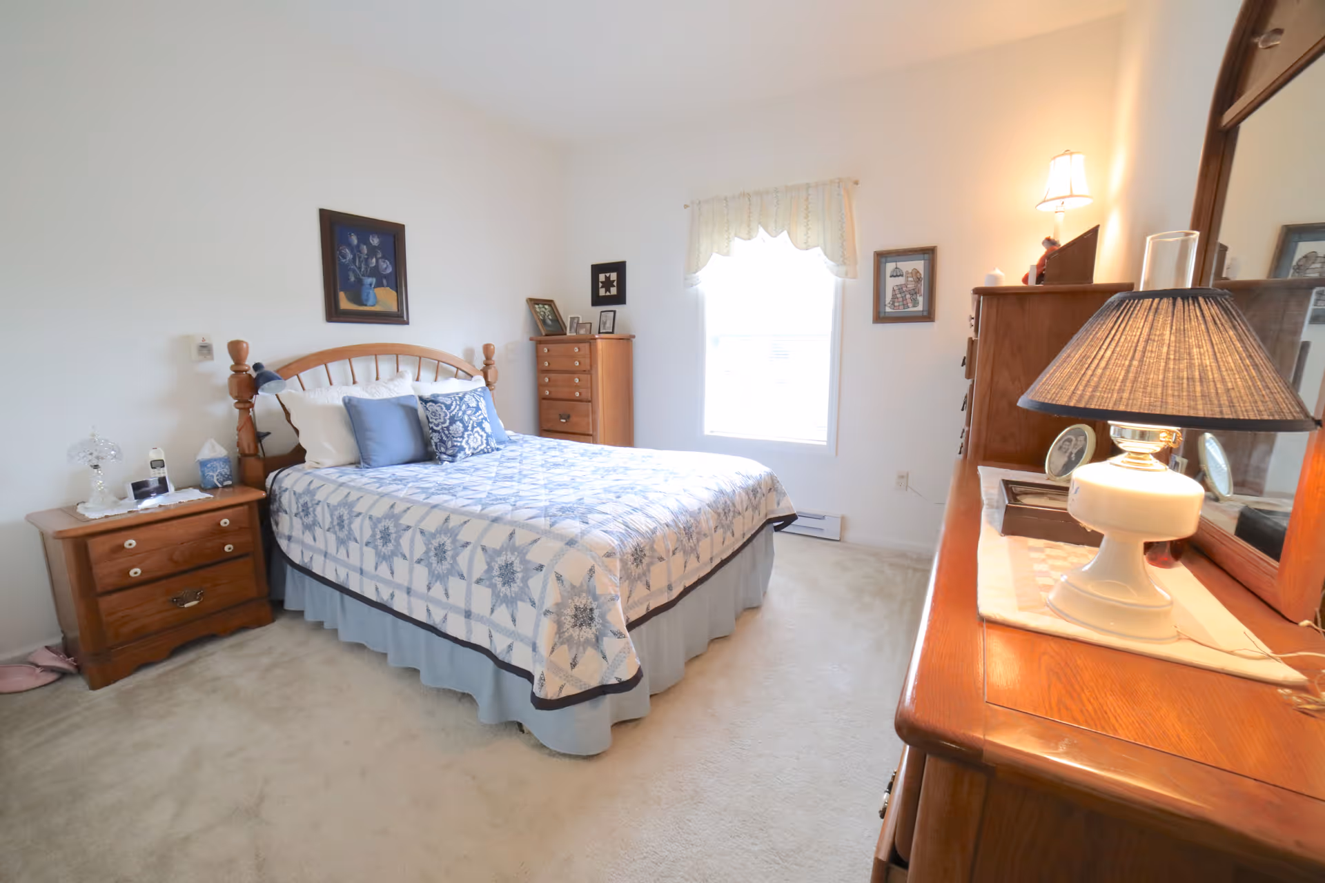 A cozy, well-furnished bedroom with a queen bed, nightstands, dresser, and lamps.