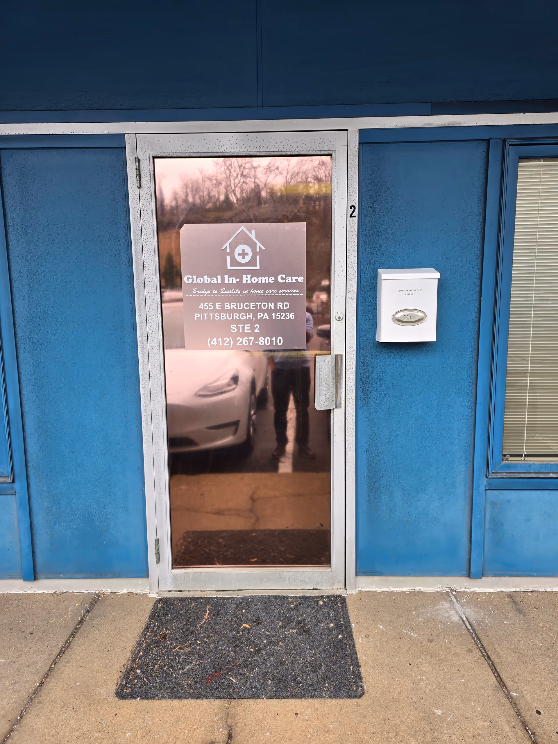 Blue exterior building with glass door displaying Global In Home Care LLC sign.