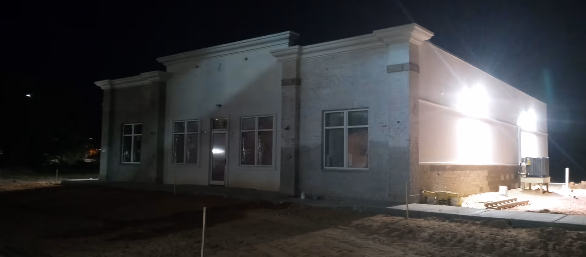 Nighttime exterior of a single-story senior living facility with illuminated entrance.