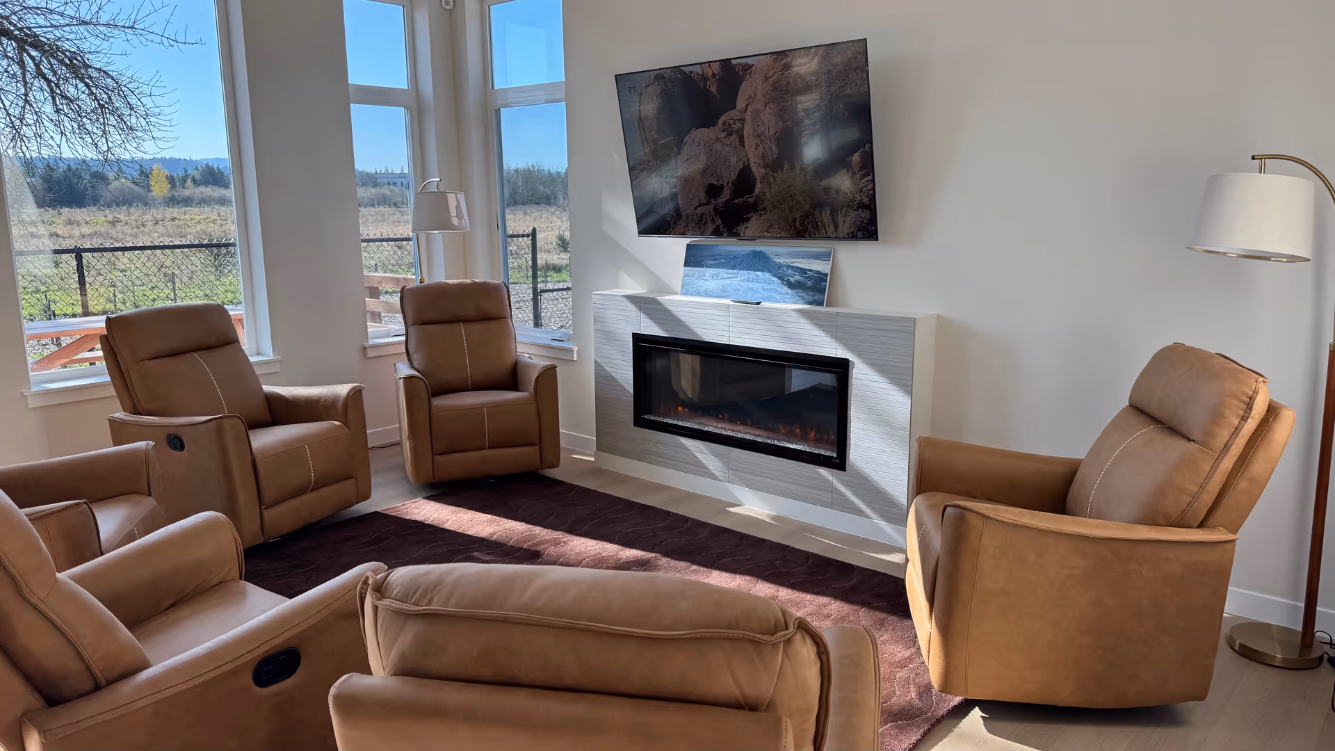 A cozy living room with tan leather recliners around a fireplace and TV.