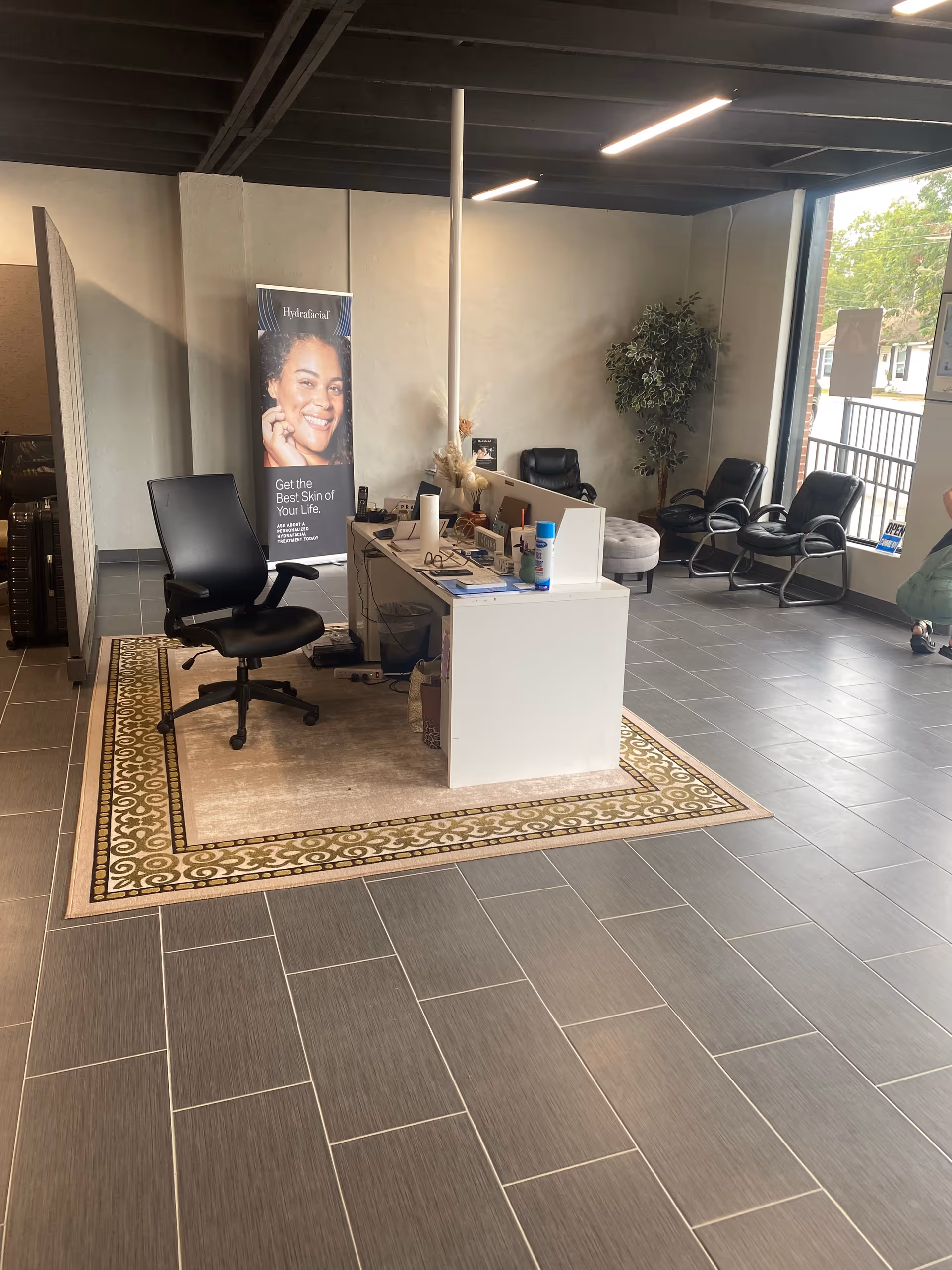 Indoor reception area with white desk, banner, and black waiting chairs.