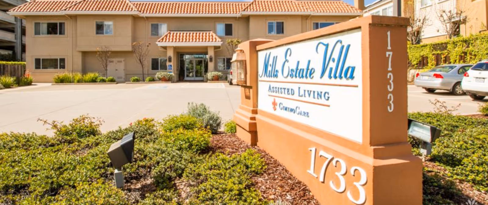 Exterior view of Mills Estate Villa Assisted Living with sign and landscaping