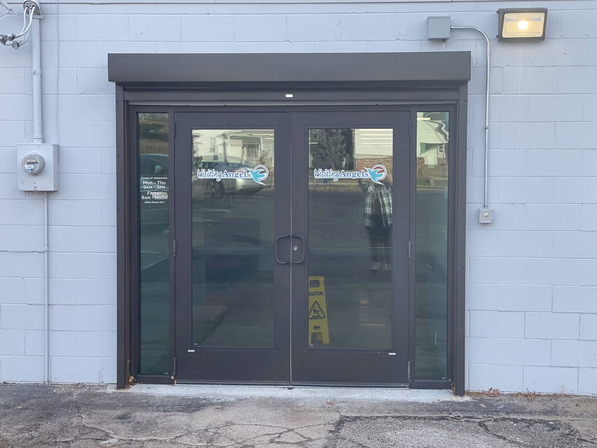 Double glass doors display the Visiting Angels logo at a gray building entrance.