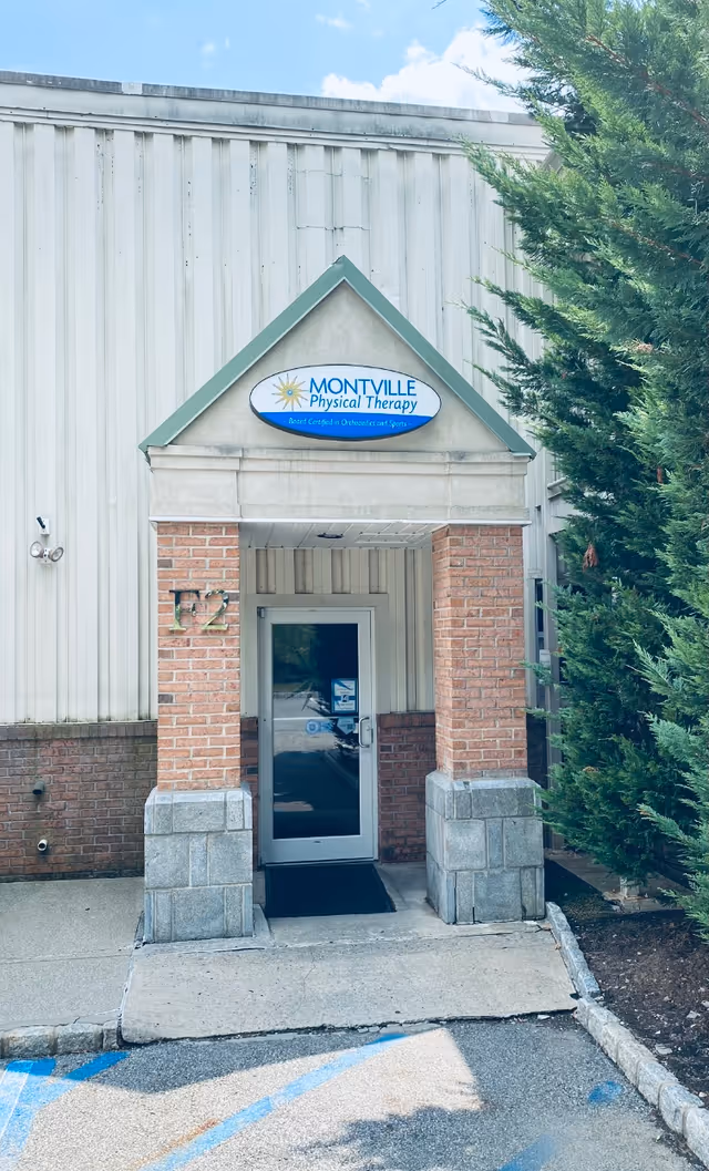 Front entrance of Montville Physical Therapy building with brick columns and glass door.