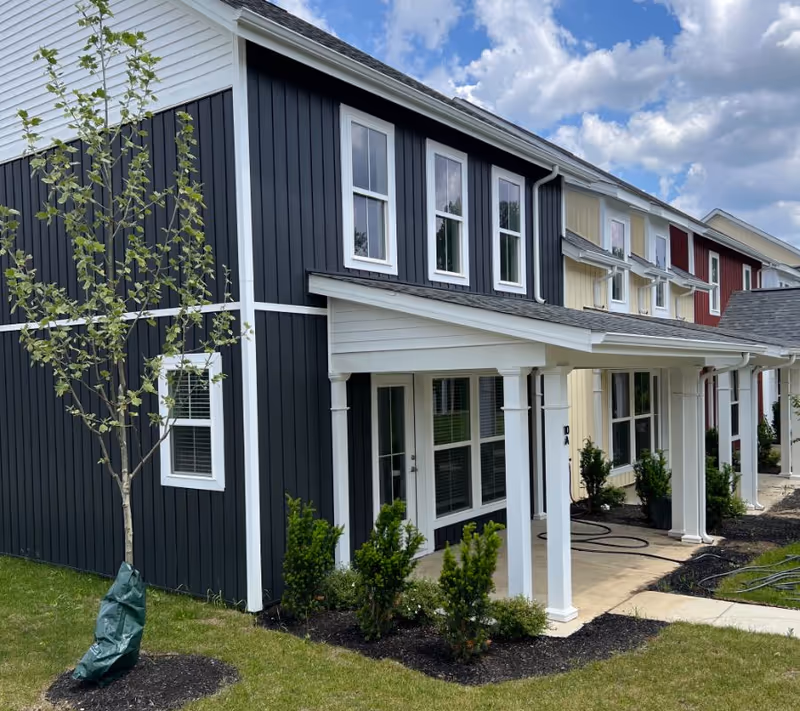 Exterior view of a townhome-style senior living complex with porches and landscaping.