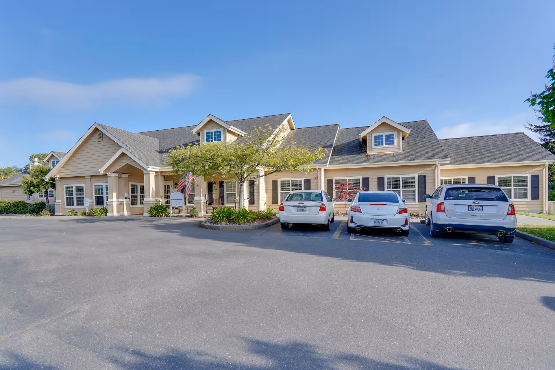 Long, single-story senior living building with a front entrance and parked cars.