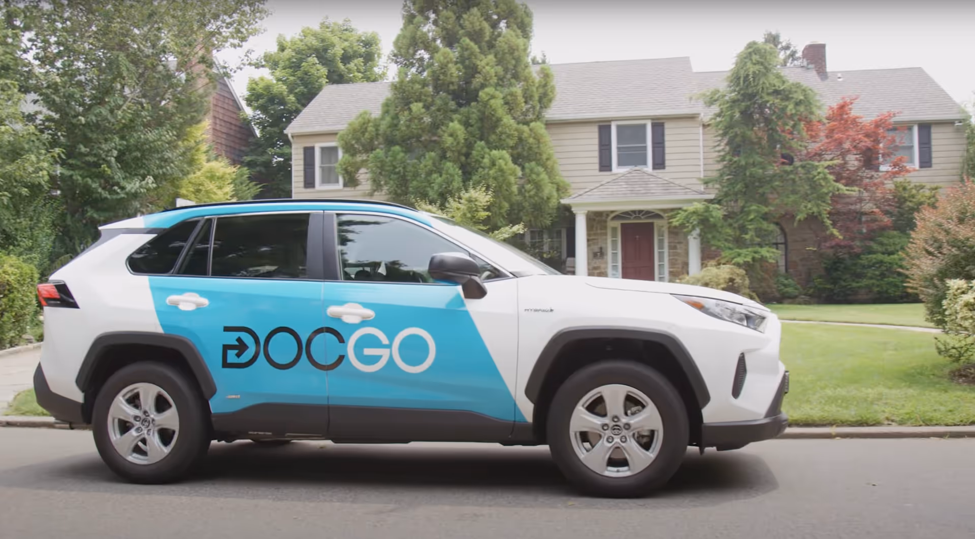 DocGo mobile urgent care SUV parked on a suburban street in front of a house.