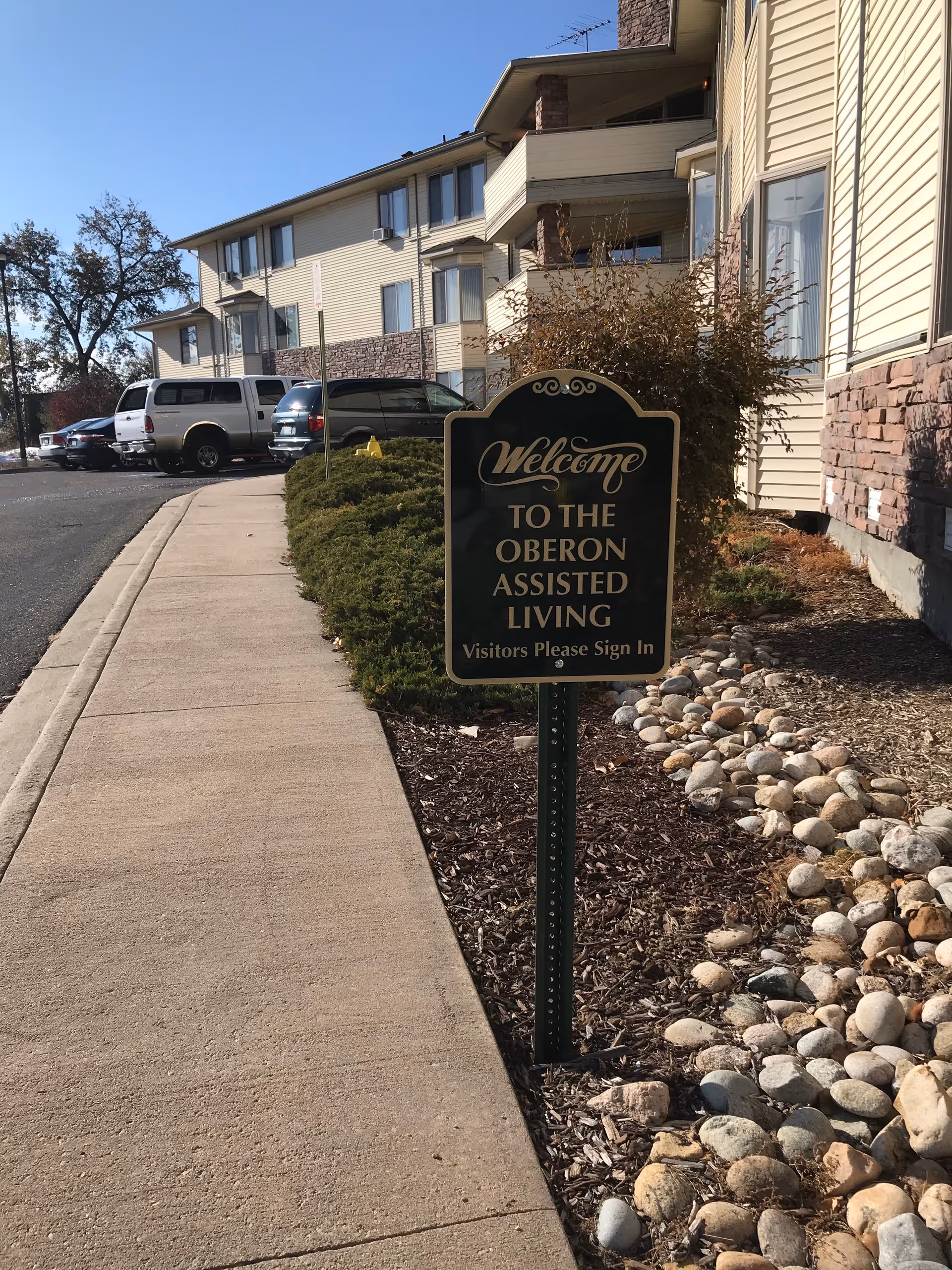 Exterior view of Oberon Assisted Living with a welcome sign near the sidewalk.