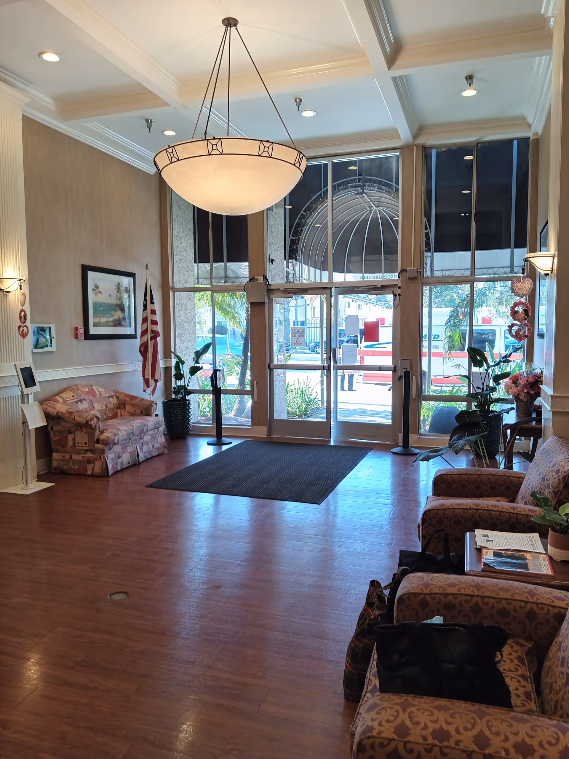 Bright lobby with seating, plants, magazines, and large glass doors.
