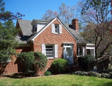 Brick cottage-style senior living home (Tapp Family Home) with a white front door and landscaped yard.