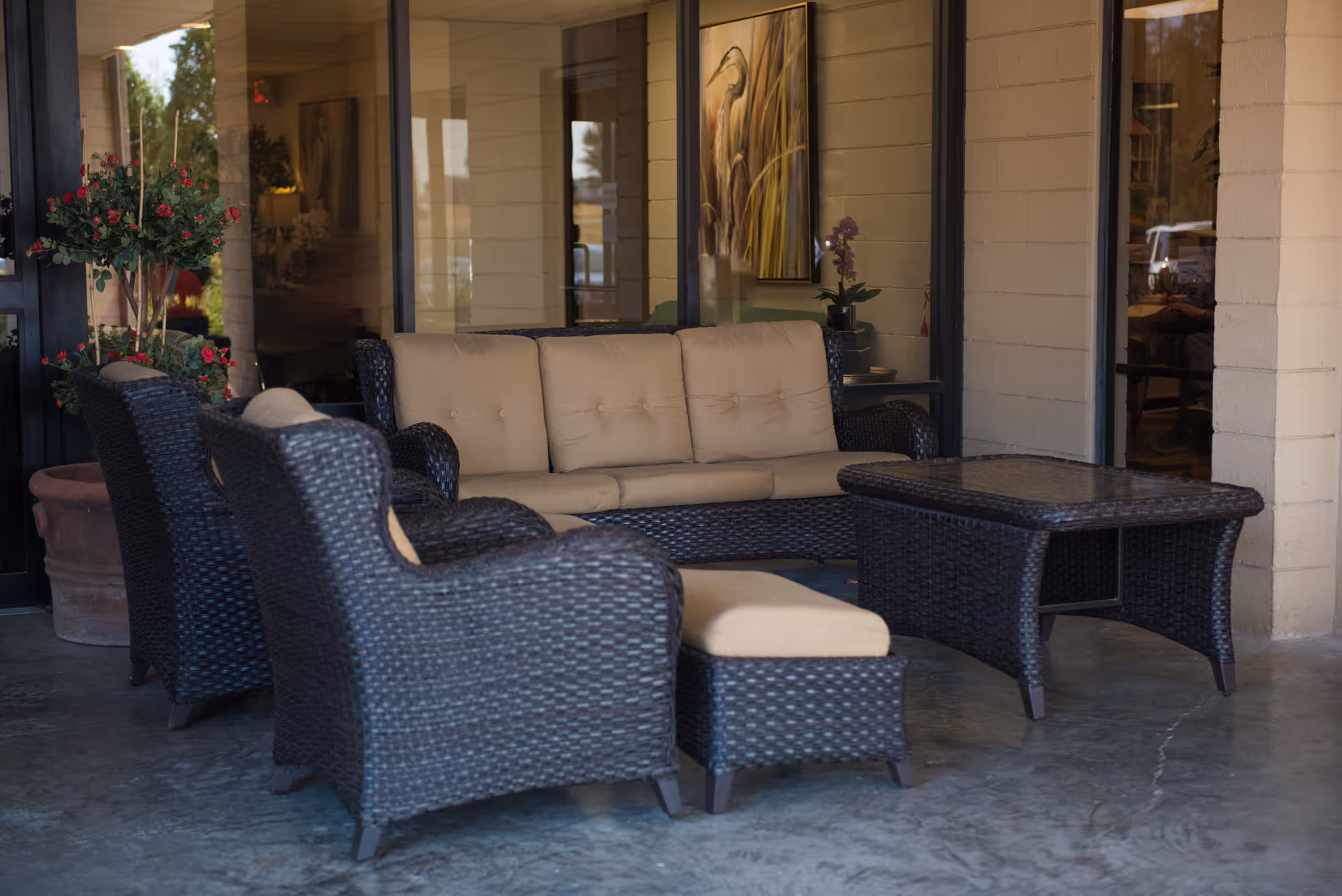 Wicker outdoor seating on a covered patio outside a building entrance.