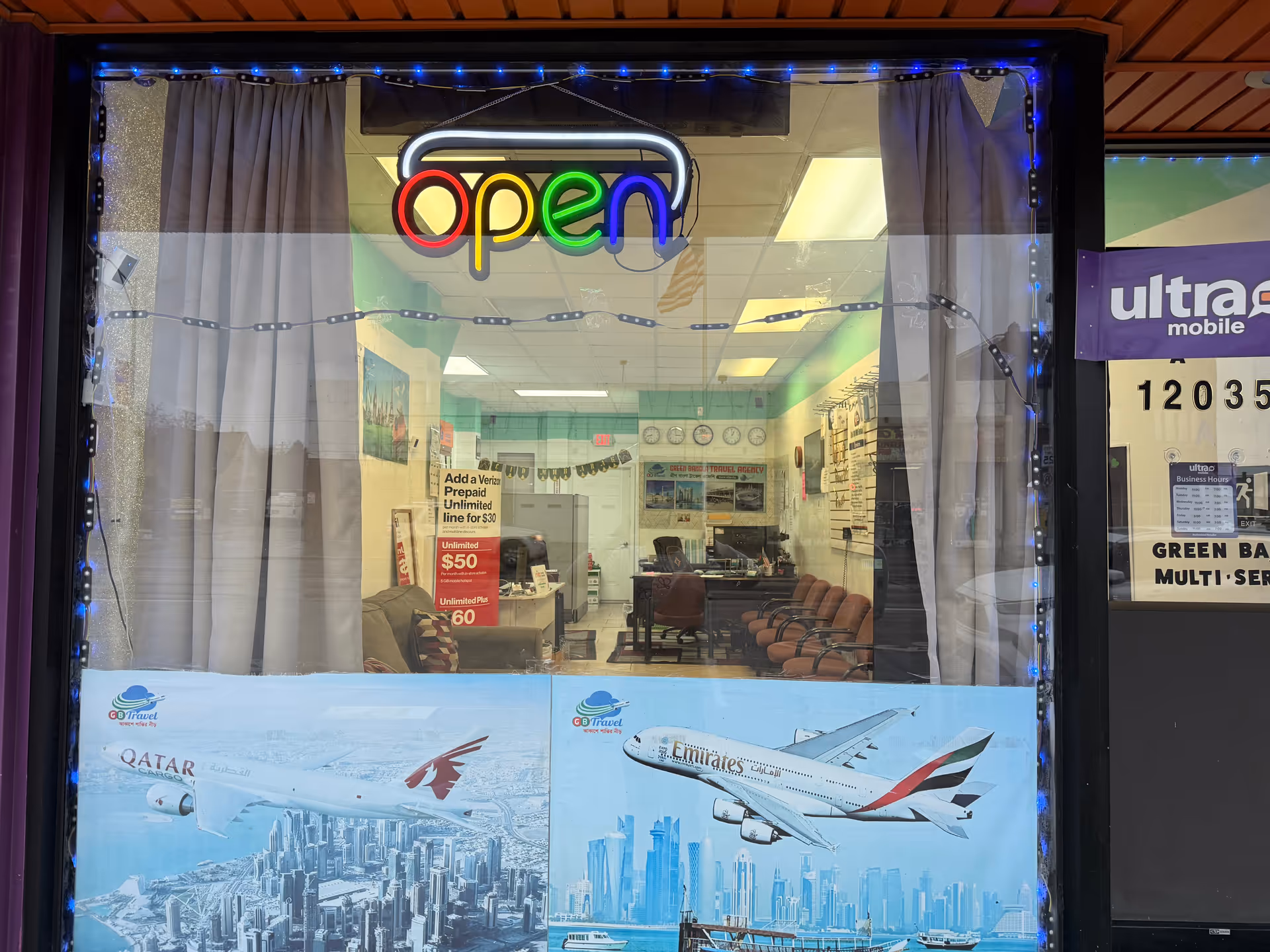 Neon 'open' sign over a storefront window revealing a seating area inside.