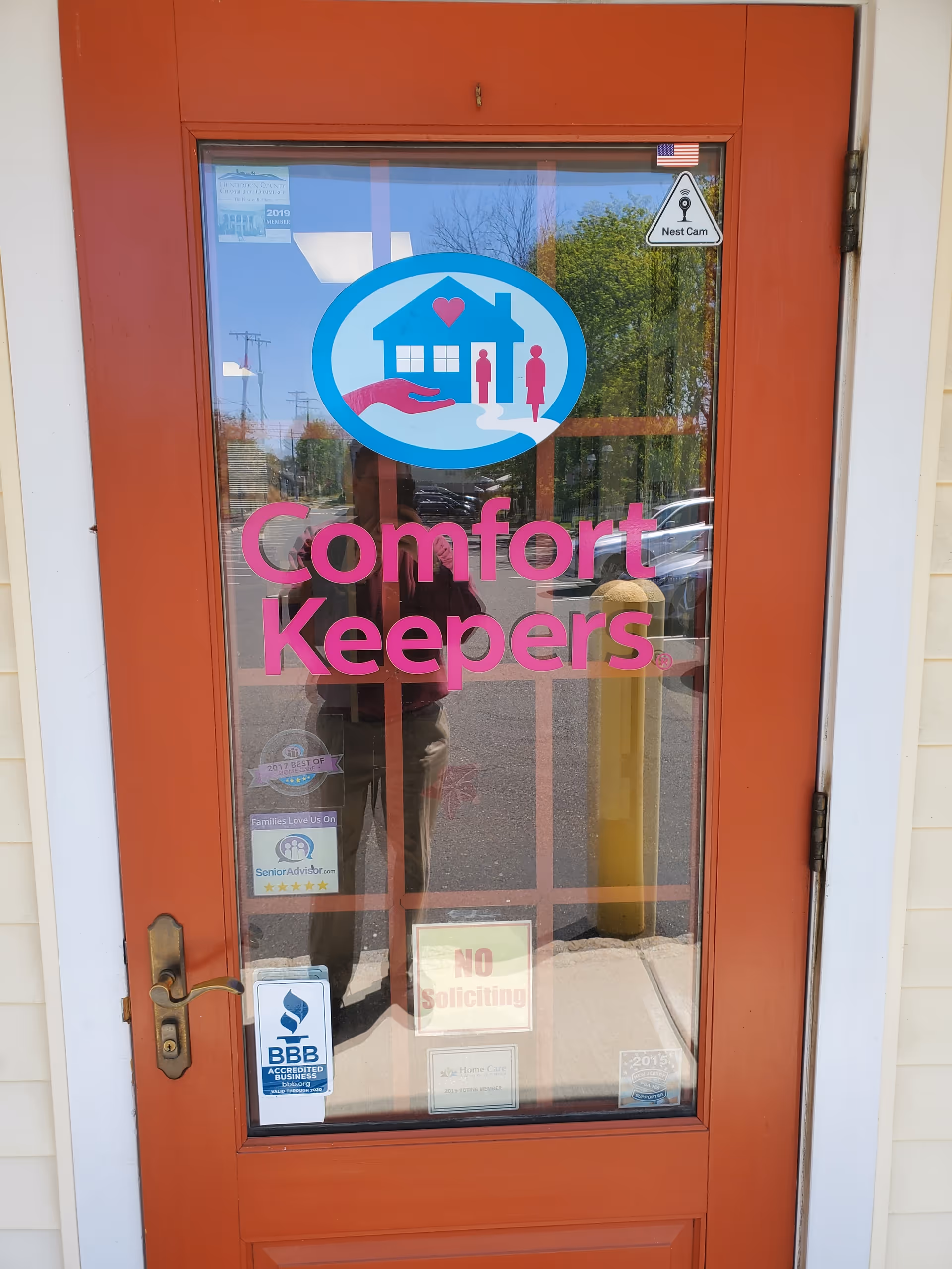 Red entry door with Comfort Keepers logo and reflective glass