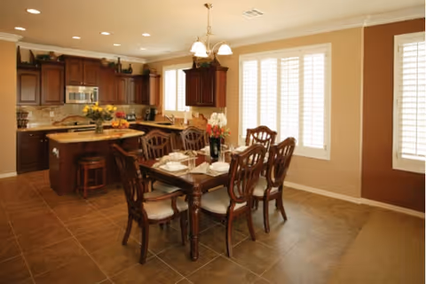Open dining room with a wooden table set for six and upholstered chairs.
