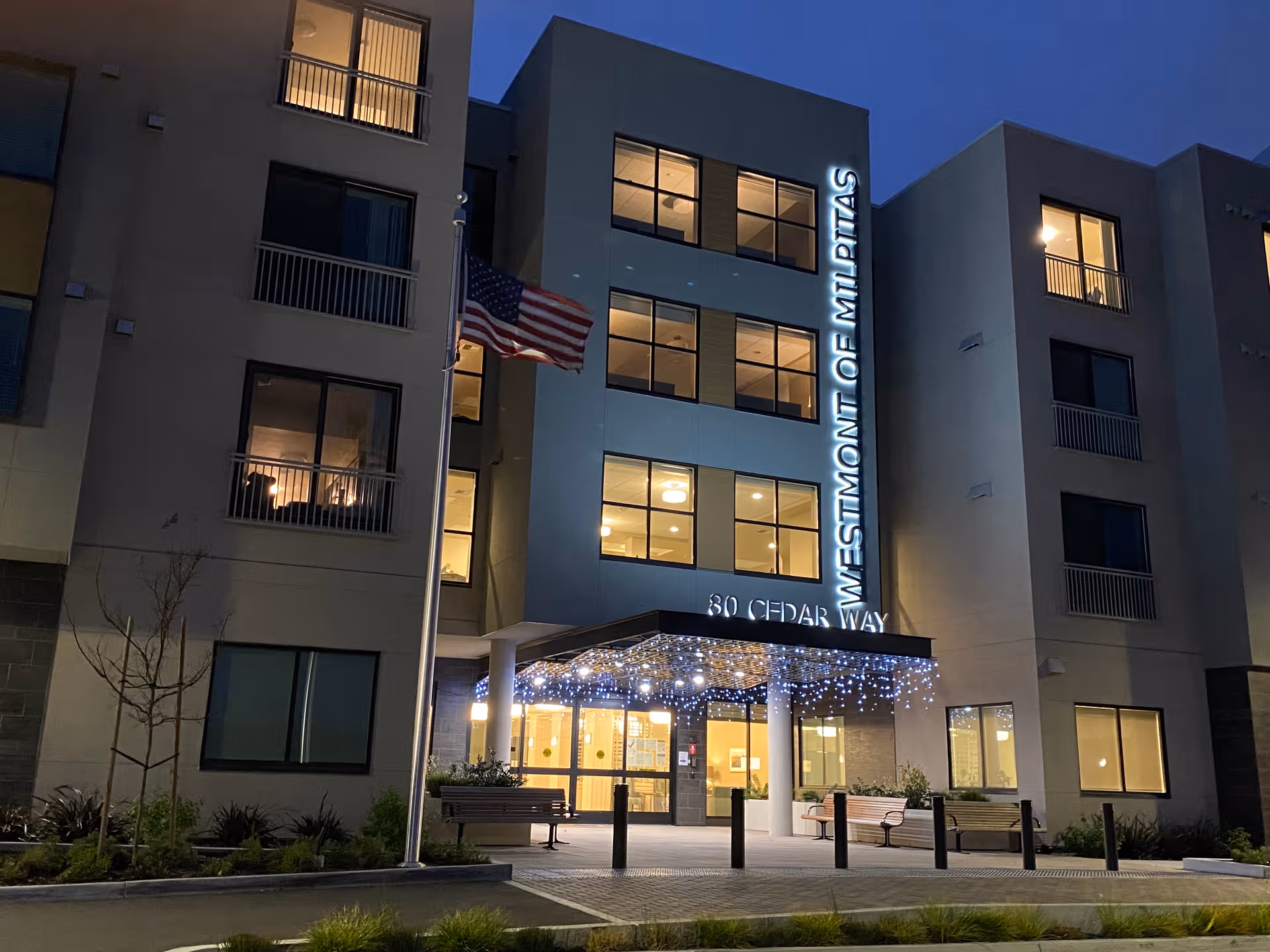 Night exterior of Ivy Park at Milpitas entrance with lights and benches.
