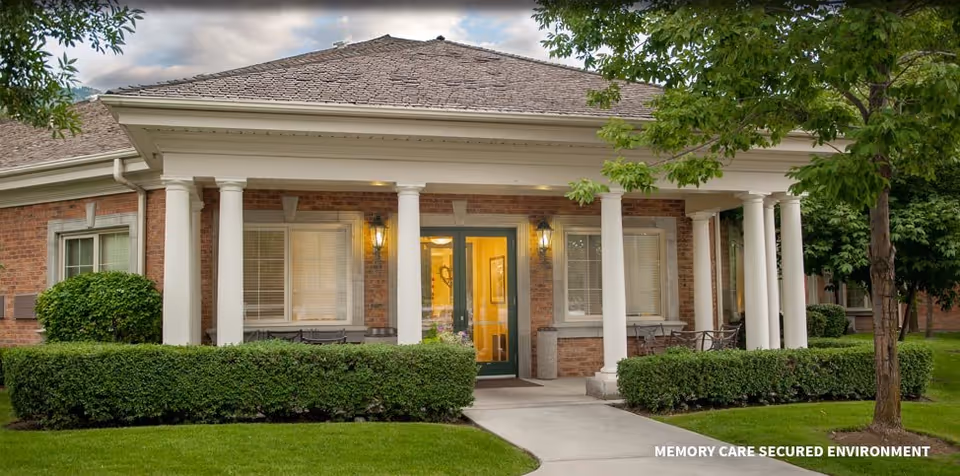 Exterior brick facility with white columns, entry doors, and manicured landscaping.