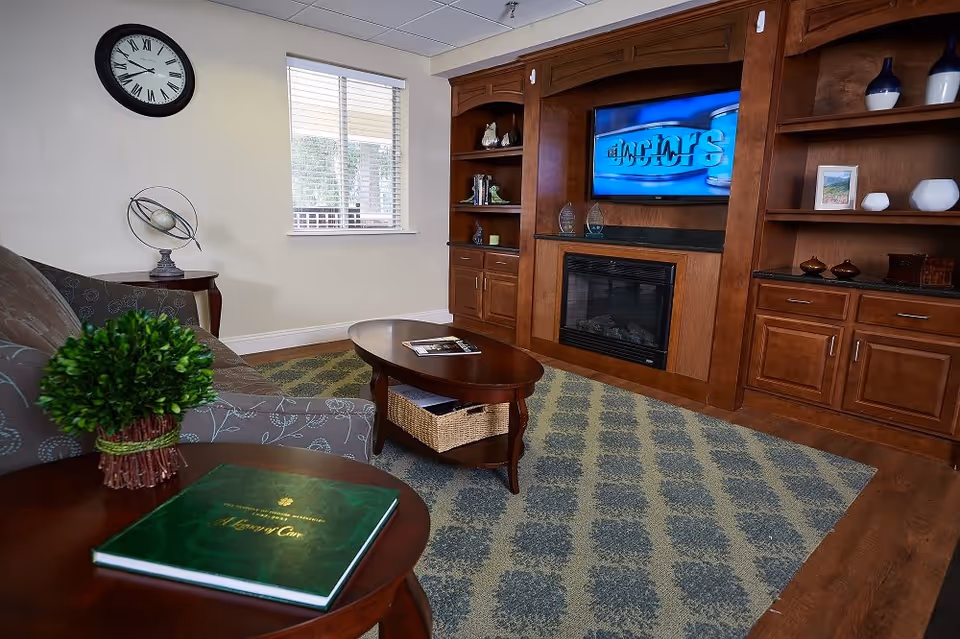 Cozy living room with a patterned rug, sofa and wooden coffee tables facing a built-in entertainment center with a TV and fireplace.