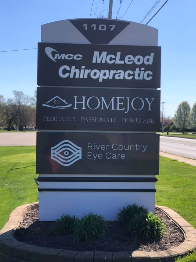 Outdoor sign for HomeJoy of Three Rivers with neighboring businesses on a landscaped base.