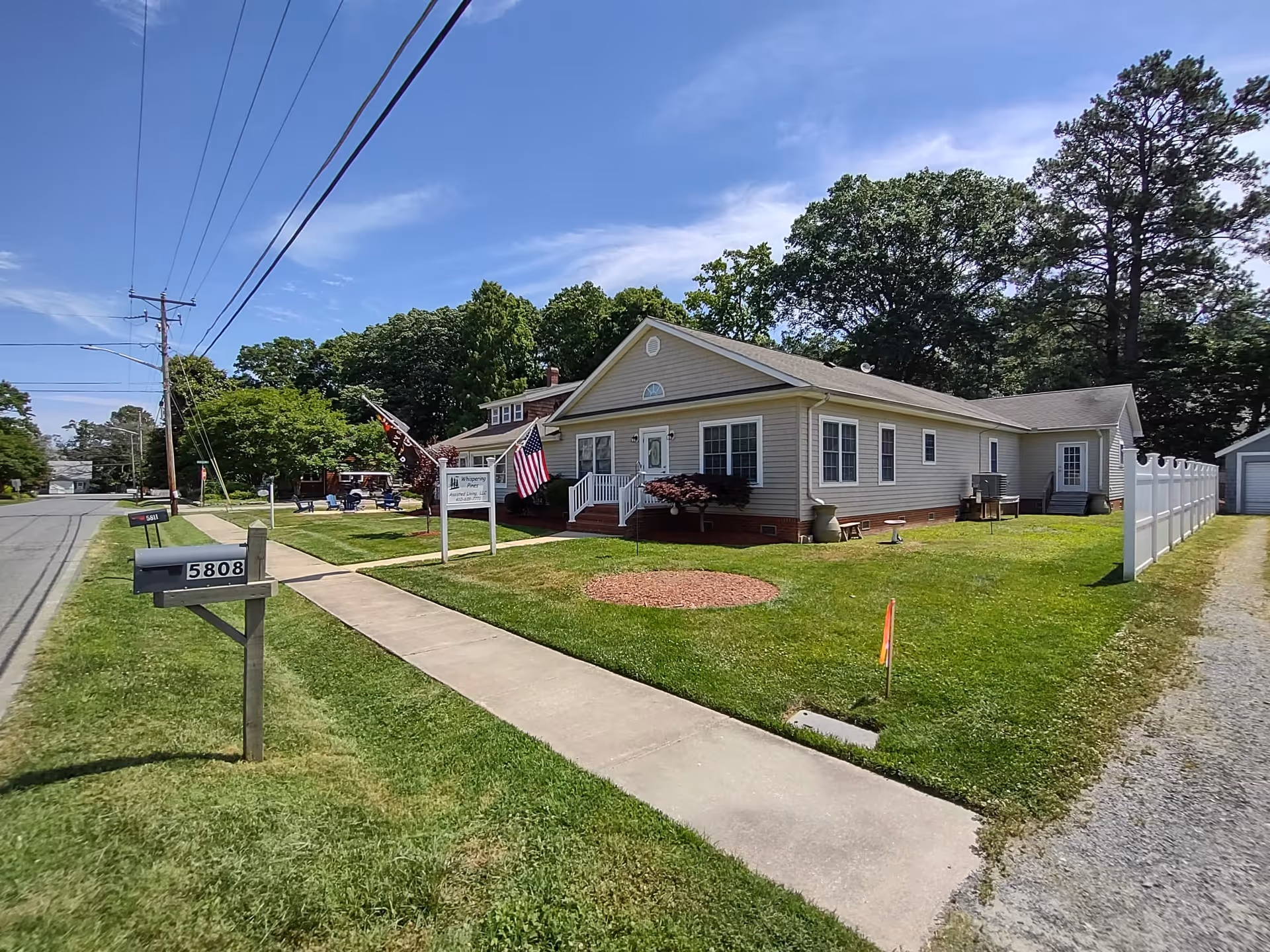Exterior view of Whispering Pines Assisted Living Facility front entrance with lawn and pathway