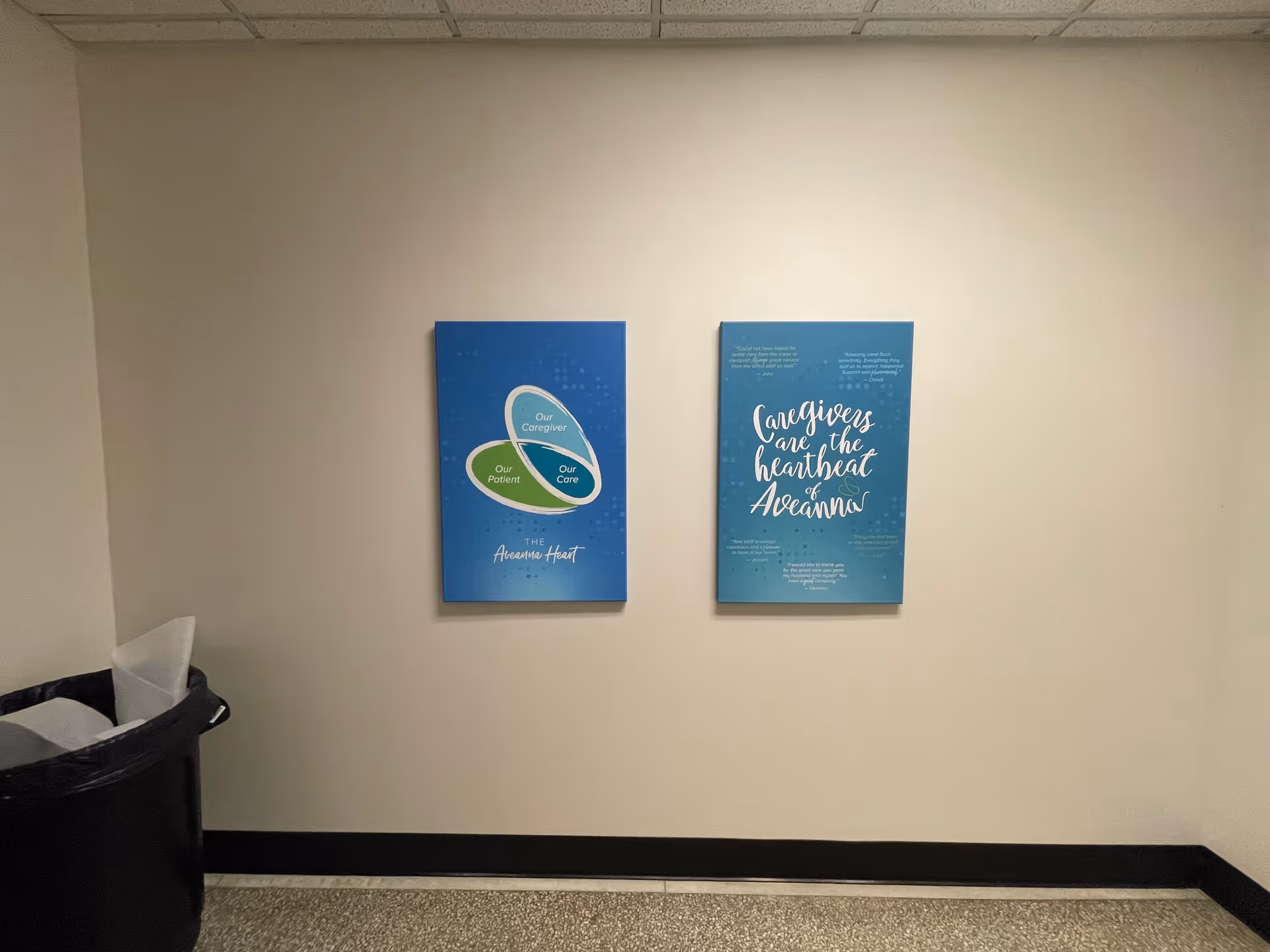 Beige hallway with two blue posters and a trash can.