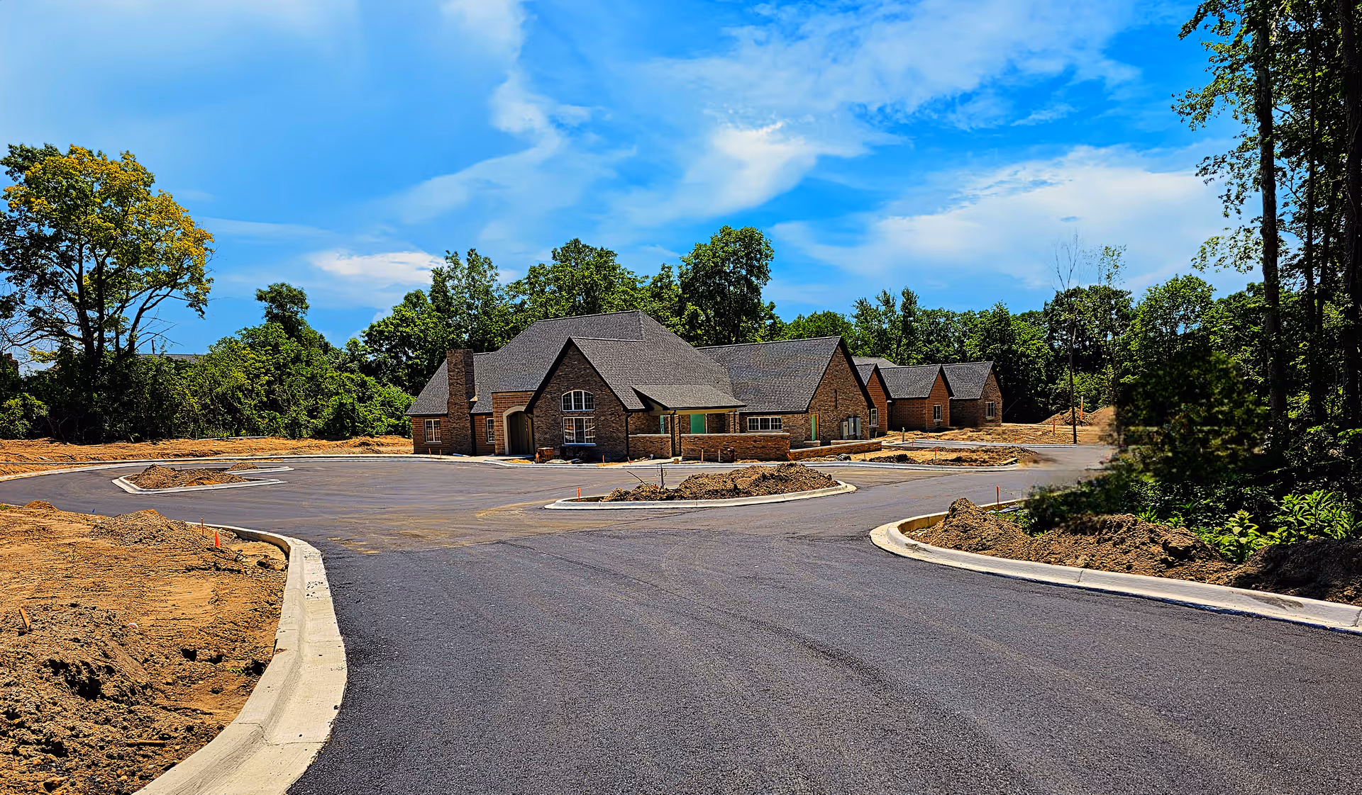 Single-story brick building with a freshly paved circular driveway and surrounding trees under a blue sky.