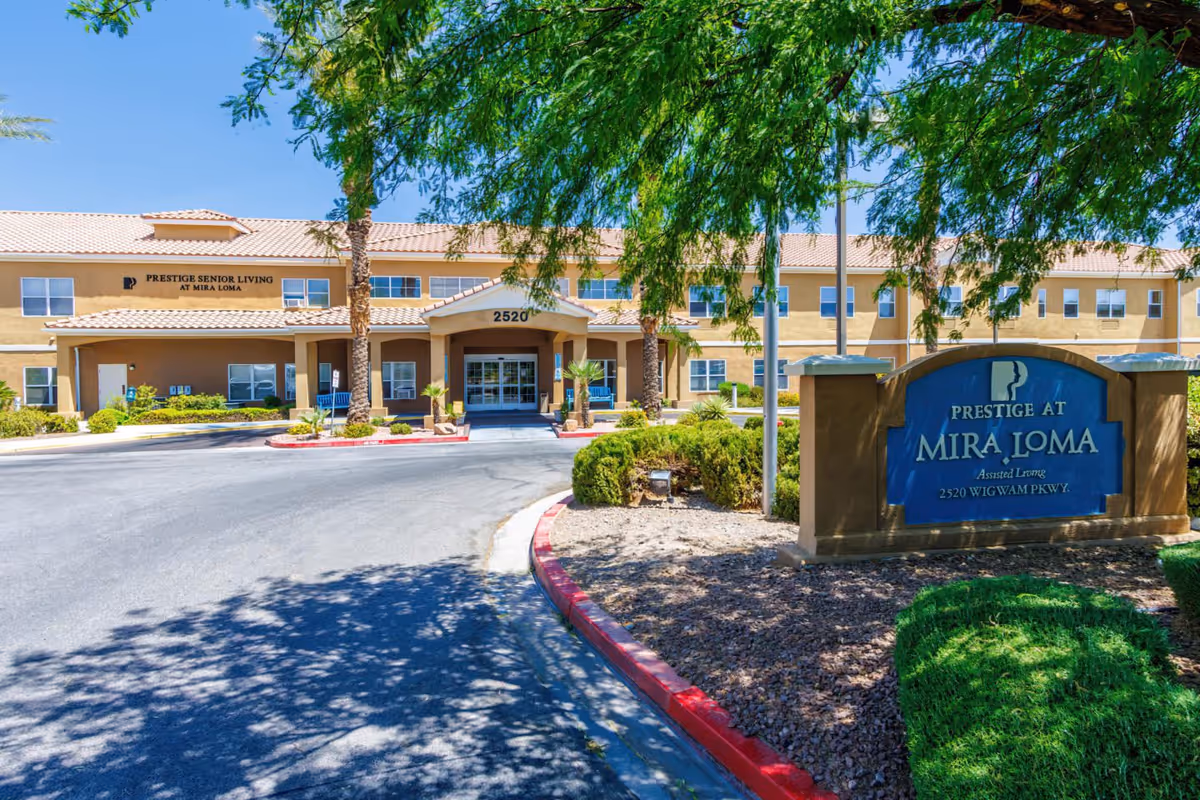 Front entrance and driveway of the Prestige at Mira Loma assisted living building with landscaped sign in the foreground.