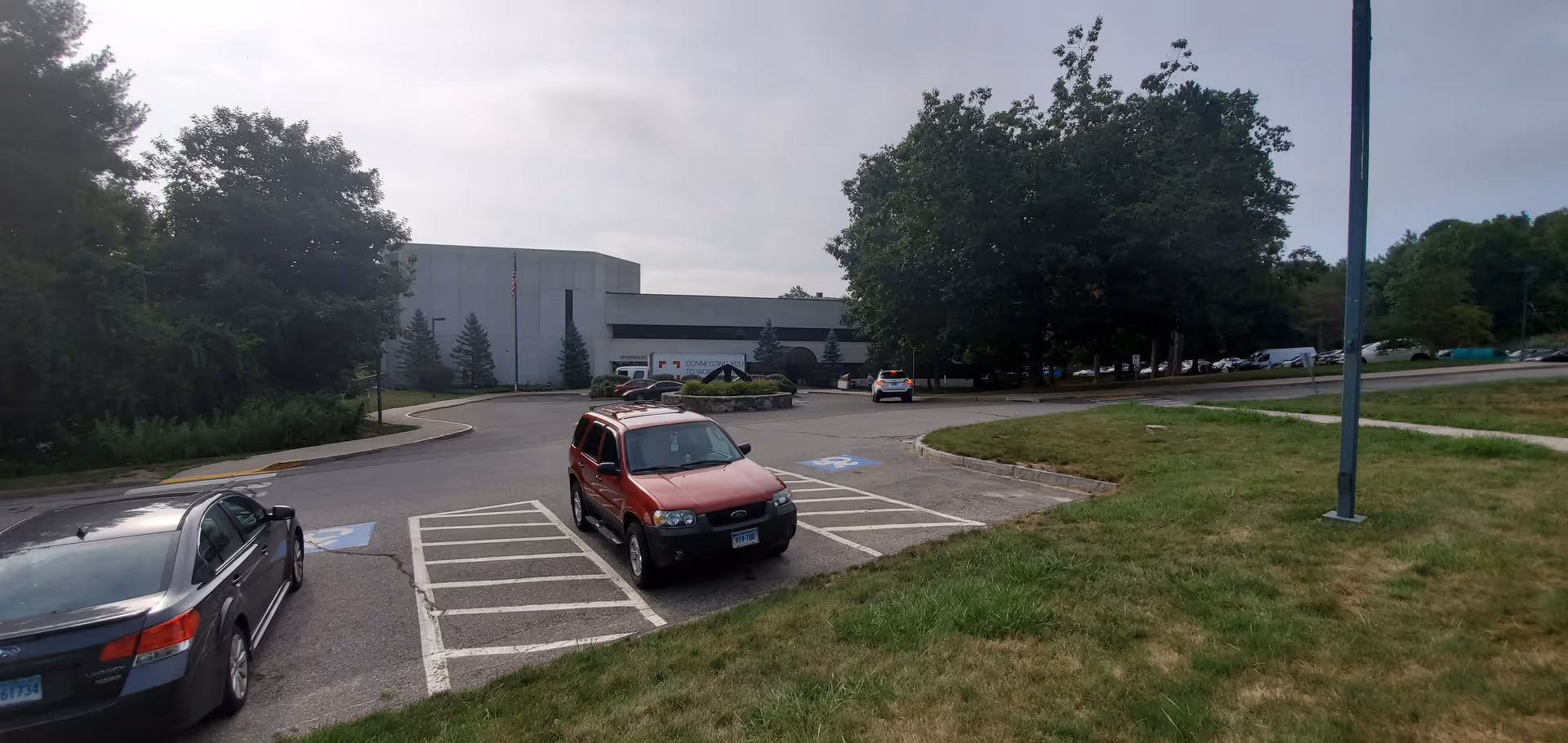 Parking lot in front of AccentCare Hospice-Connecticut building with cars and trees.